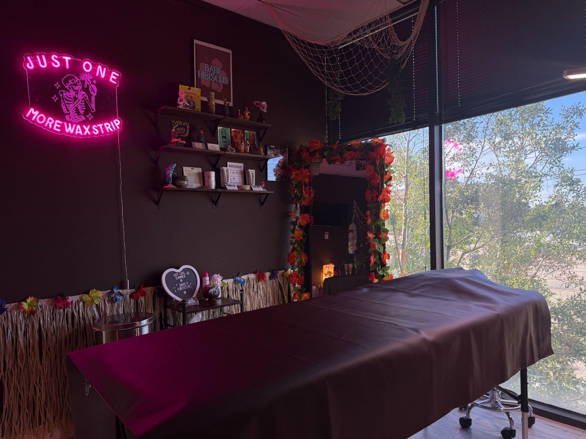 The Bare Hibiscus waxing suite with neon sign and treatment bed